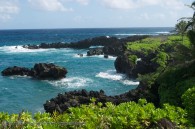 tropical shoreline with lava rocks and clear ocean water surf