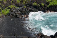 black sand beach in small cove, waves breaking on the shore