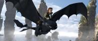 a black night fury dragon named toothless flies over the water with his rider hiccup